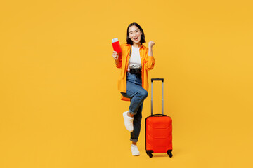 Young woman wears summer clothes hold passport ticket suitcase do winner gesture isolated on plain...