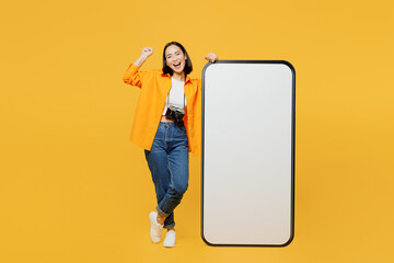 Young woman in summer clothes big blank screen mobile cell phone do winner gesture isolated on plain yellow background Tourist travel abroad in free time rest getaway Air flight trip journey concept
