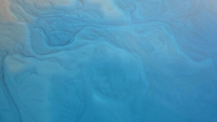 Top view of the turquoise water of a mountain lake. Clean clear water with streaks on the bottom. Patterns from a mountain river. The color shimmers from blue-green to blue. Trees in the water. Issyk