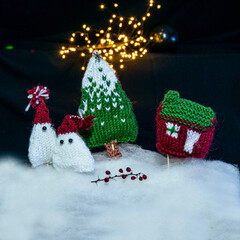 knitted trees, houses and gnomes, night view, color light painting photo, blurred background, craft concept, winter fairy tale