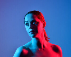 Head and shoulders close up portrait of pretty girl with expressive facial expressions, with  colourful neon gel lighting, isolated on studio background.