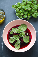 Roseate bowl with soup made of beetroot, vertical shot on a black marble background, high angle view