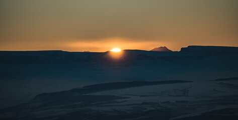 Panorama of the mountain range of the Caucasus Mountains at sunset, view of the mountain peaks in winter in the evening at sunset