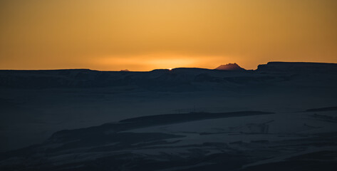 Panorama of the mountain range of the Caucasus Mountains at sunset, view of the mountain peaks in winter in the evening at sunset