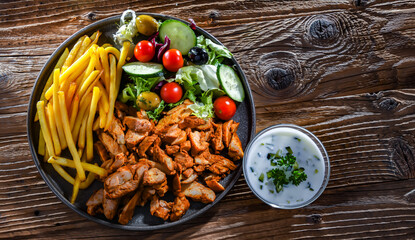 Kebab served with french fries, vegetable salad and tzatziki
