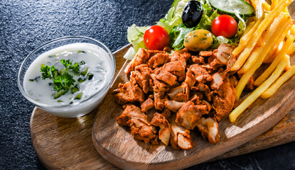 Kebab served with french fries, vegetable salad and tzatziki