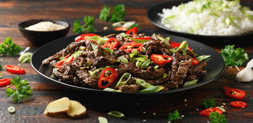 Korean beef Bulgogi with sesame seeds, chili and spring onion in a black plate