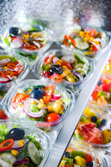 Boxes with pre-packaged vegetable salads in a commercial fridge