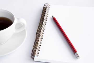pencil on blank notebook There is a coffee cup on the left side of the picture.