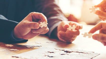 Close up Business team work holding two jigsaw connecting couple puzzle piece for matching to goals...