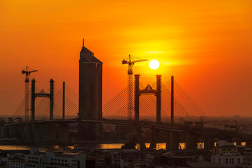 The shadow of a bridge being built reflected a beautiful sunset, and the metropolitan area was covered in pm 2.5 pollution.