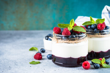 Parfait with cream or yogurt, jam and fresh berries in the glass jar. Close up. Healthy dessert or snack.