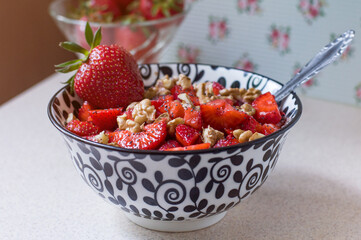 Strawberry salad with walnuts and poppy seeds in a black and white plate