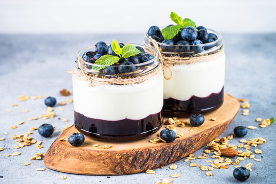 Parfait with blueberry, granola and jam in two glass jars. Healthy dessert or snack.