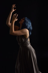  close up portrait of pretty girl with blue hair wig & elegant gown with expressive facial expressions & gestural arm poses. colourful neon gel lighting, isolated on studio background.