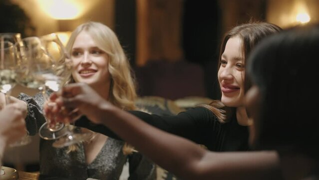 women friends party in restaurant, beautiful multi ethnic girls clincking glasses and rejoicing