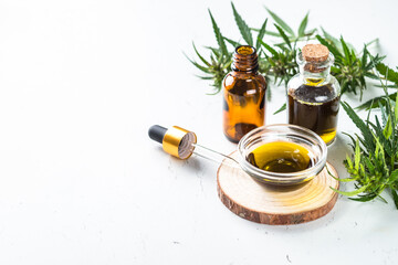 CBD oil in glass bottles and cannabis leaves at white table. Close up. Medicine and cosmetic product.