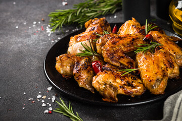 Grilled chicken wings with spices and tomato sauce at black kitchen table.