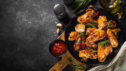 Grilled chicken wings with spices at black table. Top view with space for design.
