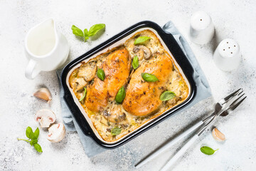 Baked chicken breast with mushrooms in cream sauce. Top view on white kitchen table.