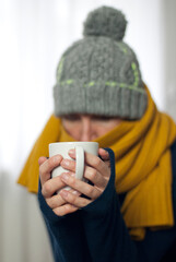 Frau zu Hause, erkältet und frierend mit Tee in der Hand