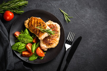 Meat steaks with fresh salad. Top view image at black table.