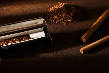 Hand-rolled cigarette, rolling machine, cigarillos, scattered tobacco on background, cigarette roll with filter, cigarette filters.