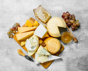 Different kinds of cheese with honey and grapes.