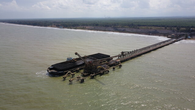 Aerial view of the activity loading coal into barges in a shipyard