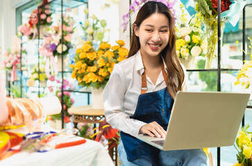 Asian Female Owner Of Florists Shop With Laptop Talking On Mobile Phone.Asia woman vlogger...