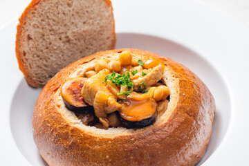 stew with pork meat, chickpeas and sausge in loaf of bread
