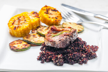 grilled pork steak with zucchini and corn served with black quinoa