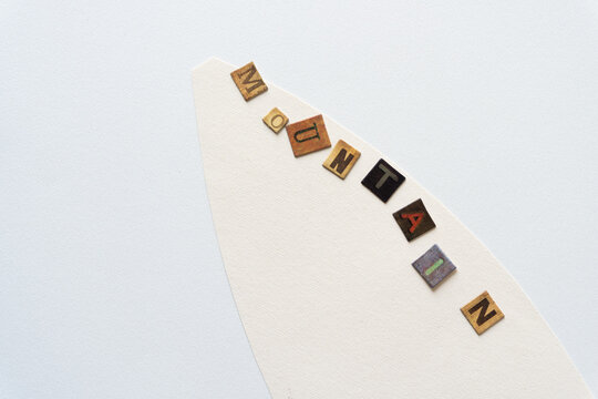 the word "mountain" composed chipboard tiles with vintage style letters on a textured ivory paper shape