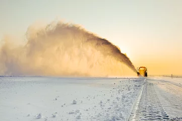 Fotobehang Bulldozer removes snow from the ice road at sunset. © Alexey Bakharev