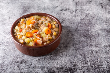 Spelled and legume soup served on an earthenware plate. Single balanced dish, suitable for a vegan diet, rich in vitamins, minerals and iron.