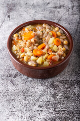 Spelled and legume soup served on an earthenware plate. Single balanced dish, suitable for a vegan diet, rich in vitamins, minerals and iron.