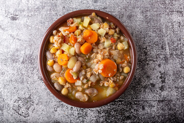 Spelled and legume soup served on an earthenware plate. Single balanced dish, suitable for a vegan diet, rich in vitamins, minerals and iron.