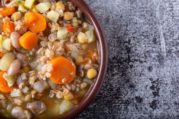 Spelled and legume soup served on an earthenware plate. Single balanced dish, suitable for a vegan diet, rich in vitamins, minerals and iron.