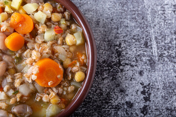 Spelled and legume soup served on an earthenware plate. Single balanced dish, suitable for a vegan diet, rich in vitamins, minerals and iron.
