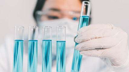 Asian woman Scientist experimental in laboratory with test tube and beaker for medical research