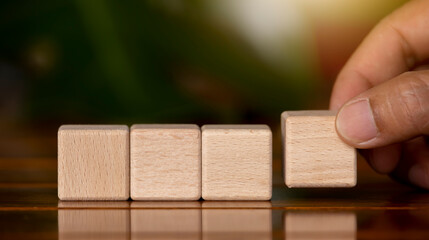 Hand picks up 4 empty wooden blocks arranged in a row for adding messages.