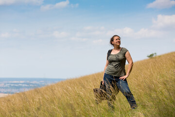 Naklejka na ściany i meble woman standing at hillside in a meadow 