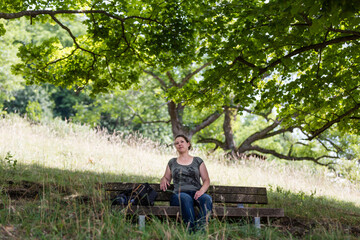 Naklejka na ściany i meble brunette woman resting on bench in shade of trees