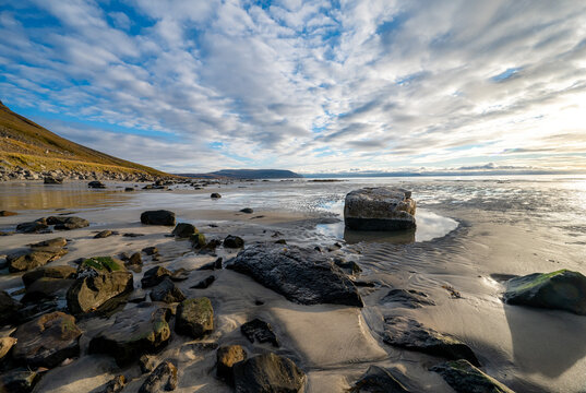 Rising sun at a sandy beach with beautiful rocks in the Westfjords in the morning, Iceland, stock photo, Europe