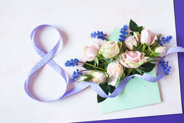 Bouquet of roses and spring flowers muscari in an envelope and number eight from a ribbon on pink, violet paper, women's day march 8 car