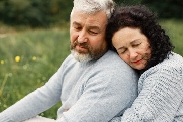 Senior couple sitting on a grass in a park and hugging