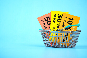 Shopping basket with discount flyers and vouchers on blue background.. Sales promocional poster.