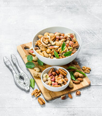 Different types of nuts in bowls with green leaves.