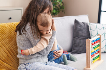 Mother and son playing with abacus hugging each other at home