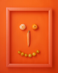 Carrot, cherry tomatoes and clementines in frame on orange
